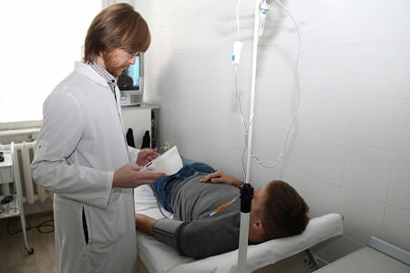 Врач общается с пациентом под капельницей